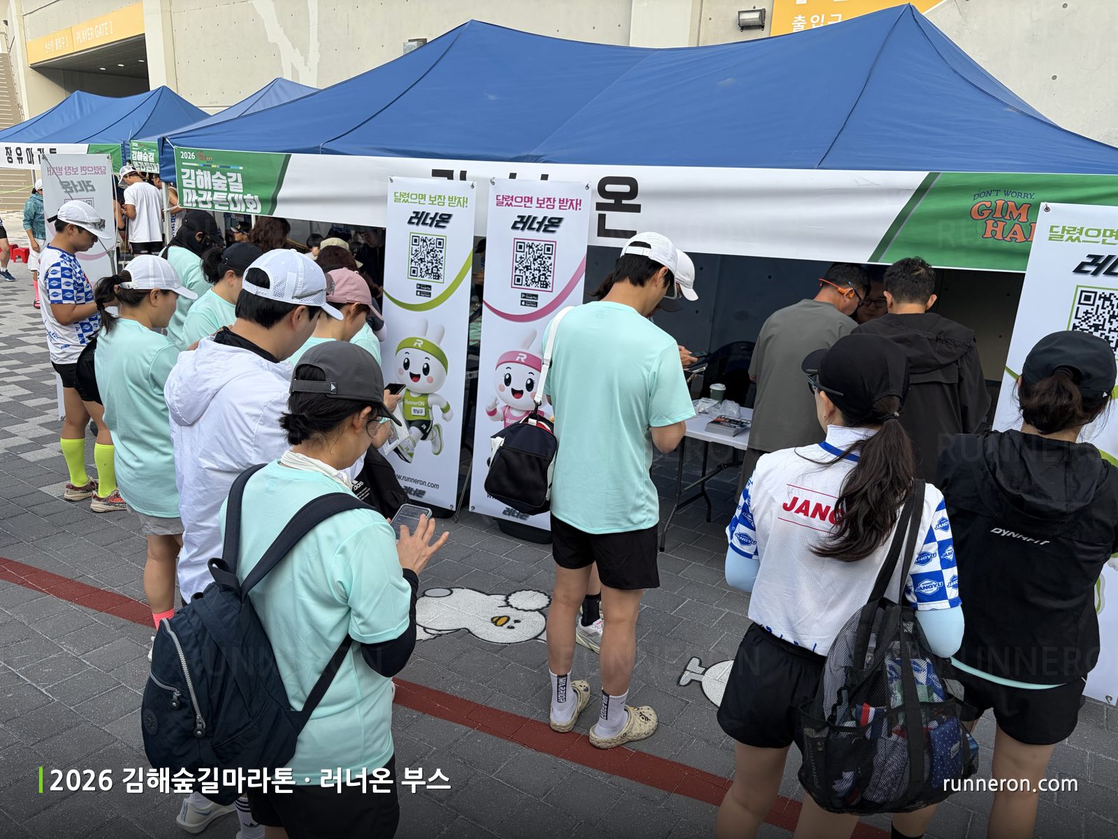 2026 김해숲길마라톤 러너온 부스 앞에 줄 서서 QR코드로 앱을 다운로드하는 러너들